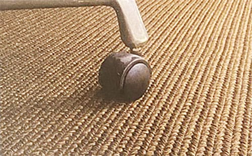 Primo piano di una ruota di sedia appoggiata su stuoia Extè da interno o esterno.