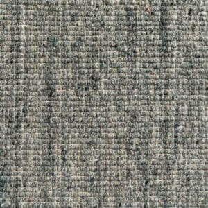 Primo piano di un tessuto grigio strutturato che mostra un motivo a griglia realizzato con fili grossi. Il materiale appare spesso e resistente, con sottili variazioni di colore lungo la trama: una vera e propria bozza automatica nell'artigianato tessile.