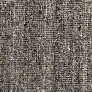 Primo piano di un tessuto grigio, strutturato e intrecciato - Bozza automatica - con macchie di giallo e varie tonalità di grigio, che mostra una superficie ruvida e fibrosa e un distinto motivo a griglia.