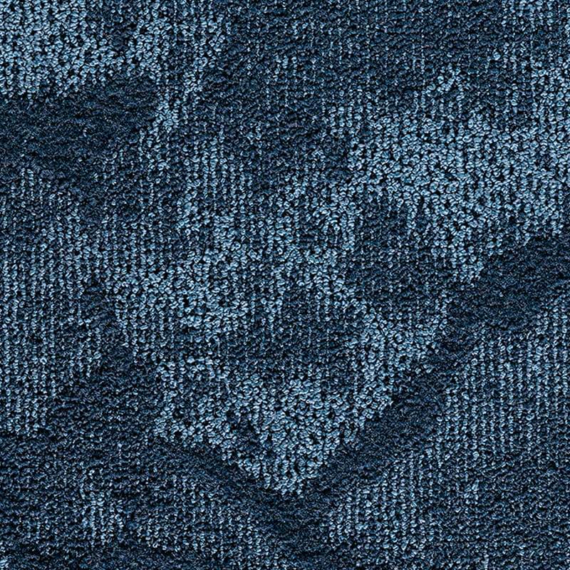 Primo piano di un tappeto blu strutturato con un sottile motivo geometrico e astratto in varie tonalità di blu, caratterizzato dallo stile raffinato di Bozza automatica.