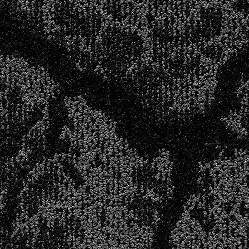 Primo piano di un tessuto strutturato con un motivo astratto e screziato in varie tonalità di grigio e nero. La superficie appare leggermente ruvida, con forme e ombre sottili e irregolari che ricordano un disegno di Bozza automatica.